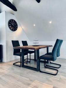 een eettafel met stoelen en een klok aan de muur bij FeWo Lindenallee II in Nordhorn