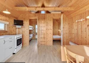 a wooden cabin with a kitchen and a dining room at Camping Vesterhav in Harboør