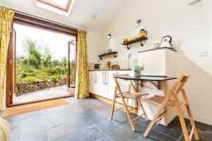 eine Küche mit einem Tisch und Stühlen sowie einem großen Fenster in der Unterkunft The Old Piggery. Cornwall in Liskeard