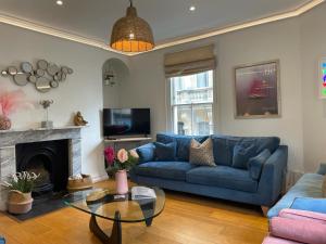 sala de estar con sofá azul y chimenea en Hot Bath House, en Bath