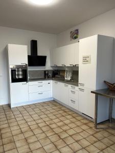 una cocina con armarios blancos y una mesa. en Minas Ferienwohnung, en Dormagen