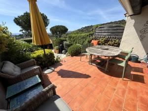 d'une terrasse avec une table et un parasol jaune. dans l'établissement Mas 2 chambres avec vue mer, piscine, Wi-Fi - FR-1-726-10, à La Croix-Valmer 5 autres photos