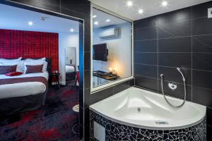une chambre d'hôtel avec une baignoire et un lit dans l'établissement Hôtel Garrigae Villa La Florangerie - Piscine extérieure, à Strasbourg