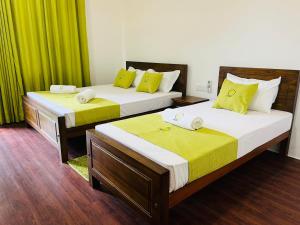 two beds in a room with green curtains at Apartment lake kurunegala in Kurunegala