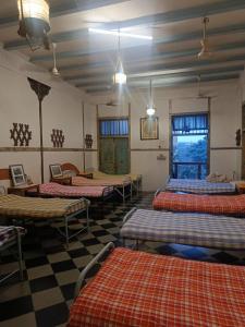 a room with four beds and a checkered floor at Hostel Vasantashram CST Mumbai in Mumbai