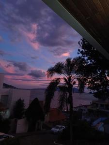 una palmera frente a una puesta de sol en Residencial Rodrigues en Florianópolis