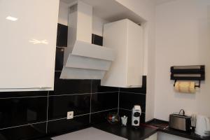 a kitchen with white cabinets and black and white tiles at Apartamenty Uniejow "prywatne kapiele termalne" in Uniejow