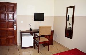 a room with a desk with a television and a chair at Kunta Kinte Hotel in Accra