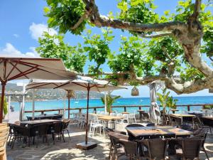 an outdoor restaurant with tables and chairs and the ocean at Akwabay - Les Villas du Cap in Le Lavandou