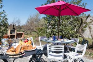 a table with a pink umbrella and food on it at Villa Kenavo - Maison familiale avec vue mer in Île dʼAix