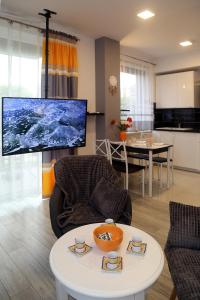 ein Wohnzimmer mit einem großen TV und einem Tisch in der Unterkunft Apartamenty Uniejow "prywatne kapiele termalne" in Uniejów