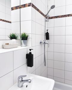 a white tiled bathroom with a shower and a sink at Hotel Alex Berlin in Berlin