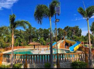 a pool with a slide in a resort with palm trees at Hacienda Antonio Function Hall and Resort in Pampang