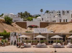 ein Resort mit Stühlen und Sonnenschirmen vor einem Gebäude in der Unterkunft Domina coral Bay diving Spa casino sultan beach in Sharm El Sheikh