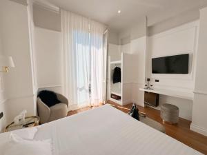 a bedroom with a bed and a television and a chair at Rechigi Park Hotel in Modena