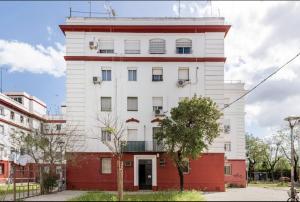 un grand bâtiment blanc avec une fondation rouge dans l'établissement Acogedor y precioso apartamento en Sevilla, à Séville