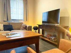 uma sala de estar com uma televisão de ecrã plano e uma mesa em In de Witte Dame Hotel Bar Kitchen Apartments em Grubbenvorst