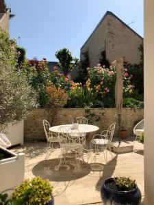 Un patio con mesa y sillas y flores. en Les Pensees Chambre Hemingway, en Orléans