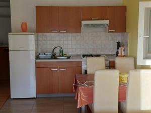 a kitchen with a white refrigerator and wooden cabinets at Apartman STUDIO 2+2 in Žuljana