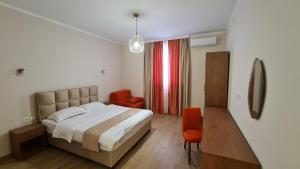 um quarto com uma cama e 2 cadeiras laranja em Hotel Laguna em Podgorica