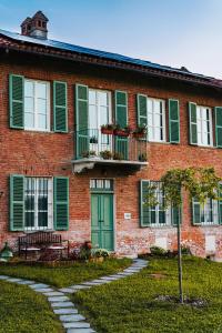 um edifício de tijolos com persianas verdes e uma porta verde em Bed & Breakfast Barbera e Tulipani em Scandeluzza