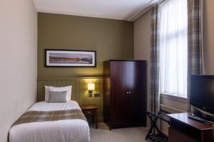 um quarto de hotel com uma cama e uma televisão em Rosslea Hall Hotel em Rhu