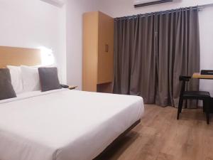 1 dormitorio con 1 cama blanca grande y escritorio en Hotel Samrat, Mumbai en Bombay