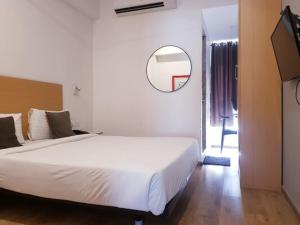 a bedroom with a large white bed and a mirror at Hotel Samrat, Mumbai in Mumbai