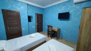 a blue room with two beds and a television at Volidam Hotel in Karmana