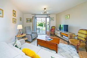 ein Wohnzimmer mit einem weißen Sofa und einem TV in der Unterkunft Maison Lutène - Avec jardin terrasse in Sartilly