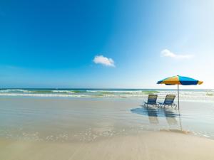 due sedie e un ombrellone su una spiaggia di Sunglow Resort 305 a Daytona Beach