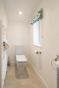 a white bathroom with a toilet and a window at Annie's House in Thorpeness