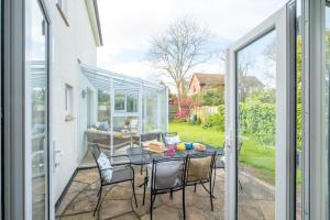 a patio with a table and chairs and a glass house at Annie's House in Thorpeness