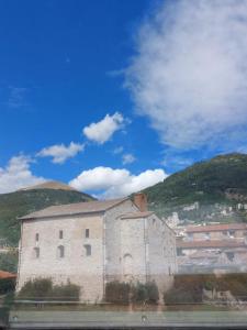 ein großes Backsteingebäude mit Bergen im Hintergrund in der Unterkunft Affittacamere Via Carducci in Gubbio