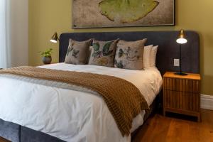 1 dormitorio con 1 cama grande con sábanas y almohadas blancas en Wytham Manor House, en Ciudad del Cabo