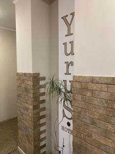 a wall with a sign and a plant on it at Yurus Hostel in Lviv