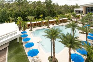 einen Blick über einen Pool mit Palmen und blauen Sonnenschirmen in der Unterkunft JW Marriott Orlando Bonnet Creek Resort & Spa in Orlando