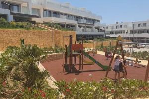 two children playing on a swing set in a playground at Camporrosso Pool View Apartment in Finestrat