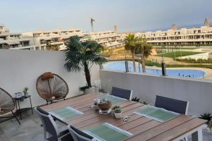 a wooden table and chairs on a balcony with a pool at Camporrosso Pool View Apartment in Finestrat