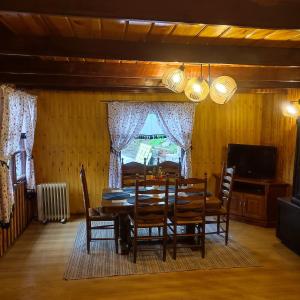 a dining room with a table and chairs and a television at Domek na Skarpie Łutynowo gmina Olsztynek in Olsztynek