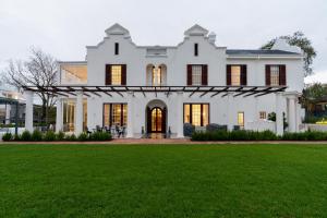 a white house with a green lawn at Manor Boutique House in Cape Town