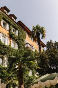 ein Gebäude mit einer Palme davor in der Unterkunft Parkhotel Mondschein, a Member of Design Hotels in Bozen