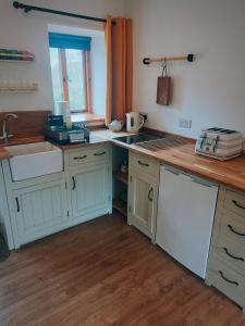 a kitchen with white cabinets and a sink at The Duddon Nest in Ulpha