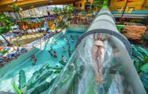 una donna che cavalca uno scivolo acquatico in un parco acquatico di Happy Place mit Sauna & Jacuzzi a Plettenberg