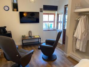 a living room with two chairs and a tv at The Ivy Barn Holbeton in Plymouth