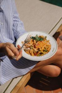 a person holding a plate of rice with a fork at Parkhotel Mondschein, a Member of Design Hotels in Bolzano