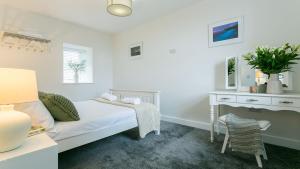 a white bedroom with a bed and a desk at Ty Capel in Pentraeth