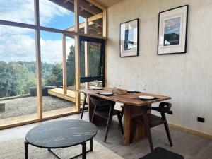 a dining room with a table and chairs and a large window at Cabaña en Rio Maullin Nek #1 in Las Quemas del Salto