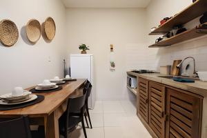 a kitchen with wooden tables and a white refrigerator at Flat 01 · Flats Japaratinga1- 200m da praia cozinha completa in Japaratinga