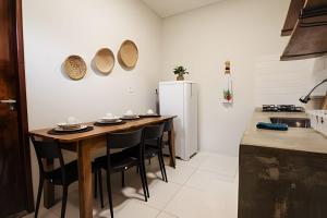 a kitchen with a wooden table and a refrigerator at Flat 01 · Flats Japaratinga1- 200m da praia cozinha completa in Japaratinga